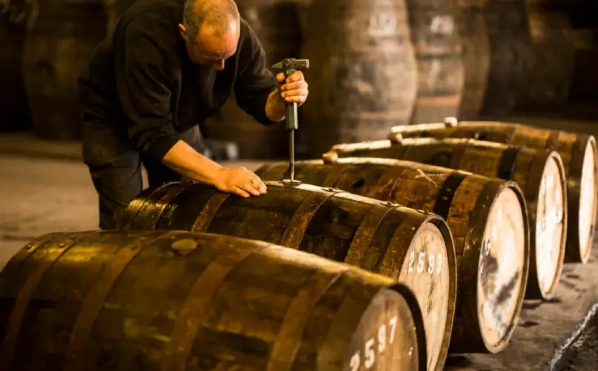 Male worker opening wooden whisky cask in whisky distillery